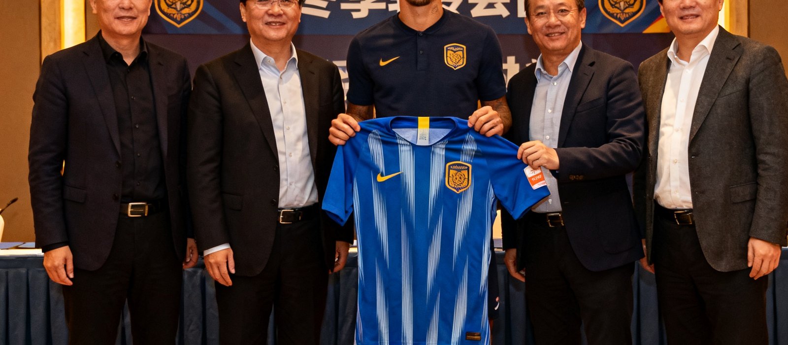 冬季转会窗球员签约仪式现场，新援手持球衣与俱乐部高层合影留念